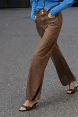 Jeans de tiro medio con diseño wide leg, confeccionados en denim color marrón con efecto lavado. Presentan cinco bolsillos, cierre frontal con cremallera y doble botón metálico.