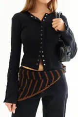 Top de manga larga color amarillo, confeccionado en tejido acanalado con cierre frontal de botones a presión metálicos. Presenta detalles de botones en los puños y un corte ajustado al cuerpo.