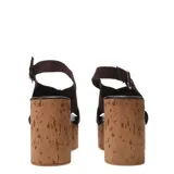 Sandalias de plataforma alta estilo cuña fabricadas en corcho. Presentan tiras cruzadas en el empeine de gamuza color marrón oscuro y cierre mediante pulsera con hebilla metálica al tobillo.