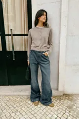 Chaqueta de punto color beige, de manga larga y corte corto, con cuello redondo y puños terminados en puntilla blanca a contraste.