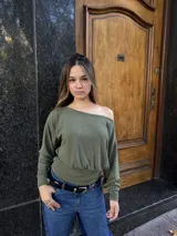 Buzo de cuello bote con diseño de hombro descubierto, confeccionado en tela angorina elastizada. Presenta un corte amplio en la parte superior y ajustado en la cintura, con mangas largas.