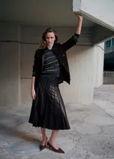 Falda midi plisada de cuero sintético en color marrón oscuro, con diseño acampanado y talle alto.