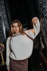 Sweater tejido a mano en lana merino y viscosa con lurex, color crudo con detalles dorados en cuello, puños y hombros. De corte holgado y cuello alto.