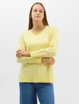 Buzo de tejido fino color amarillo, con cuello redondo, manga larga con puños acanalados y pespunte central vertical en el frente y la espalda. Presenta un ruedo ancho acanalado con tajos laterales.