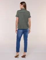 Camisa de manga corta color marrón oscuro, con cuello camisero, alforzas verticales, detalles de puntilla calada y frunces bajo el busto. Cuenta con cierre frontal de botones.