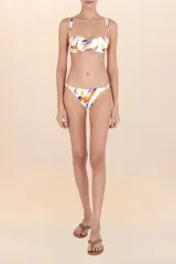 Top de bikini blanco con escote corazón y fruncido central. Presenta un estampado abstracto con pinceladas en tonos naranja, azul, rosa y negro. Tiene tirantes finos ajustables.