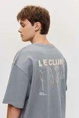 Remera blanca de manga corta, corte oversize, con estampa en la espalda de una flor sobre fondo difuminado verde y blanco.