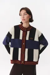 Cardigan de punto con diseño de bloques de color en tonos marrón, beige y verde. Presenta cuello redondo, cierre frontal con botones, mangas largas con hombros caídos y logo bordado en el frente.