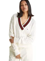 Sweater de punto color blanco hueso, con tejido trenzado (cableado) en el cuerpo y mangas. Presenta un cuello en V con ribete de rayas rojas y negras.