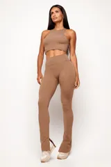 Calza de tiro alto con diseño ajustado que se ensancha hacia el bajo en silueta flare. Presenta una abertura interna en el ruedo y un recorte frontal que estiliza la figura.