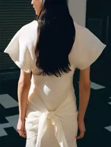 Vestido midi color crudo, con cuello drapeado, mangas cortas holgadas y diseño recto.