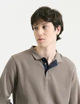 Remera de manga larga con cuello polo, confeccionada en tejido de punto canalé francés. Presenta abotonadura frontal con botones de madera y detalles a contratono en la cartera y el interior del cuello.