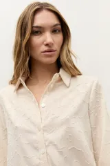 Camisa de manga larga color beige con diseño texturizado en tono sobre tono, cuello clásico y cierre frontal con botones.