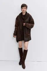 Cazadora de estilo bomber con diseño híbrido, combinando paneles de tela técnica en las mangas con un cuerpo de efecto piel desgastada y forro interior de corderito sintético. Presenta cierre frontal, cuello amplio y puños elásticos.