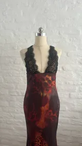 Vestido largo de microtul con estampado abstracto en tonos marrones, azules y naranjas. Tiene escote en V con encaje negro y breteles finos.