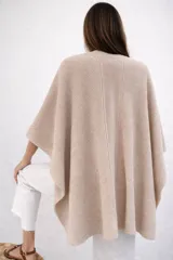 Ruana de tejido de punto en color marfil, con diseño abierto y caída fluida. Confeccionada en fibra de baby alpaca, presenta una textura suave y ligera con detalles de costuras verticales en la espalda.