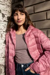 Campera puffer ultraliviana color beige, con diseño acolchado horizontal, capucha incorporada, cierre frontal y bolsillos laterales.