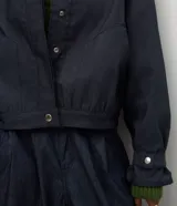 Campera bomber de denim azul oscuro, con cuello alto, cierre frontal con botones a presión ocultos, mangas largas con puños ajustables y diseño de largo corto.