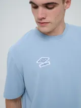 Remera Umbro de manga corta, color celeste, con cuello redondo y el logo de la marca bordado en el pecho.