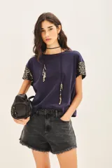 Remera de jersey 100% algodón color blanco, con cuello redondo y manga corta caída. Las mangas están completamente bordadas con lentejuelas tono sobre tono.