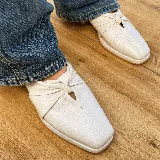 Zueco de cuero vacuno color negro, con diseño de nudo en el empeine y punta cuadrada. Cuenta con un taco bajo de madera y suela de cuero.