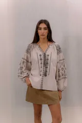 Blusa blanca con bordados en contraste de estilo bohemio, mangas amplias y diseño ligero.
