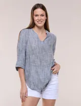 Blusa de silueta relajada y textura tramada, color azul. Presenta cuello mao abierto en V y mangas tres cuartos amplias con dobladillo ancho y pequeña abertura lateral en el puño.