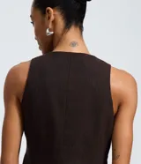 Chaleco sastre de corte estructurado en color marrón oscuro con estampado de raya de tiza. Presenta cierre frontal con botones, cuello redondo y bolsillos decorativos laterales.