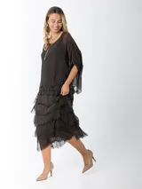 Vestido midi de seda italiana color negro, diseño dos en uno con capa superior de calce amplio, falda con volados y forro interior de algodón elastizado.