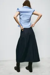 Falda midi de denim azul oscuro con tiro medio, bolsillos delanteros y costuras a contraste. Presenta un diseño con canesú estructurado y falda con frunces, cierre frontal con cremallera y botón metálico.
