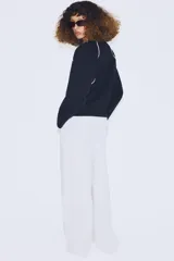 Jersey de punto de manga larga con cuello redondo, diseño en color azul marino con detalles de vivo en color blanco en el cuello y las costuras de las mangas.