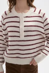 Sweater de punto a rayas horizontales en tonos marrón y blanco, con cuello redondo y cierre frontal parcial con botones. Presenta un diseño holgado de manga larga con puños y ruedo acanalados.