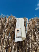 Lona de algodón a rayas verticales blancas y grises, con bolsillo plástico transparente con cierre, galón con la marca Rupia y grifa de goma.