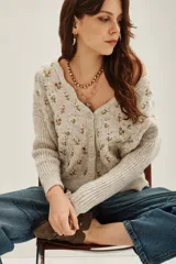 Cardigan de punto color beige con diseño de flores bordadas, escote en V, cierre frontal con botones y mangas largas con puños acanalados.