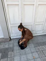 Sueco de plataforma color negro, confeccionado en material sintético tipo gamuza. Presenta una tira frontal con hebilla metálica y ojales decorativos, con suela dentada de goma.