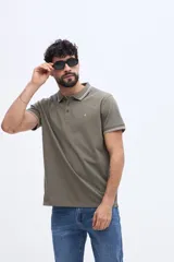 Chomba piqué de manga corta verde militar con cuello y puños tejidos a contratono en tonos claros. Cuenta con cartera de tres botones y pequeño logo bordado en el pecho.