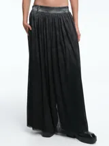 Pantalon de corte ancho y silueta amplia, confeccionado en algodón con una capa de tul superpuesta que crea un efecto visual de falda. Presenta cintura con trabillas y bolsillos laterales.