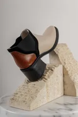 Botineta de diseño tricolor con cuerpo en tono beige, panel elástico lateral negro y talón con textura símil reptil en color marrón. Presenta un taco cuadrado robusto de color negro.