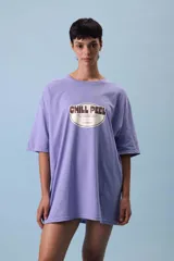 Remera oversize color lila con estampado frontal de un óvalo con la frase "Chill Peel" en marrón.