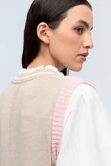 Chaleco de punto color beige con escote en V y ribete blanco.