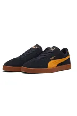 Championes Puma modelo Club Era II Suede, color negro con detalles en mostaza y suela de goma marrón.