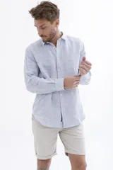Camisa celeste a rayas verticales blancas, de manga larga y corte clásico.