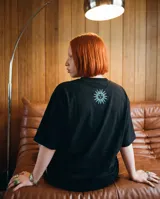 Remera negra de corte oversize, confeccionada en algodón, con estampa fotográfica central de una jugada de fútbol y texto alusivo al candombe.