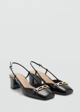 Zapato de charol negro con tacón bloque, punta cuadrada, cierre con hebilla y detalle de eslabones dorados.