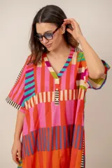 Vestido largo colorido con estampado geométrico de rayas en bloques, escote en V con botones frontales y mangas cortas holgadas.