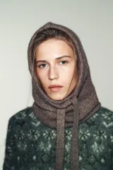 Capucha de punto canalé en color beige, con diseño envolvente y cierre frontal ajustable mediante lazada a tono.