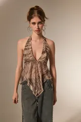 Top de cuello halter con escote profundo en V, confeccionado en tela ligera con estampado abstracto. Presenta un diseño asimétrico con terminación en punta en el frente.