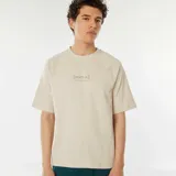 Camiseta beige de manga corta raglán con estampado frontal con el texto "[NXT-K] NO LIMITS, NO HESITATIONS".