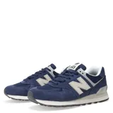 Championes urbanos New Balance modelo 574, color azul marino con detalles en gris y blanco. Confeccionados en una combinación de gamuza y malla, presentan el logo 'N' característico en los laterales y entresuela con tecnología de amortiguación.