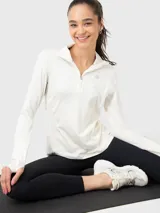 Buzo deportivo color crema de tela suave y delgada, con medio cierre frontal, cuello alto y mangas largas con orificios para los pulgares.